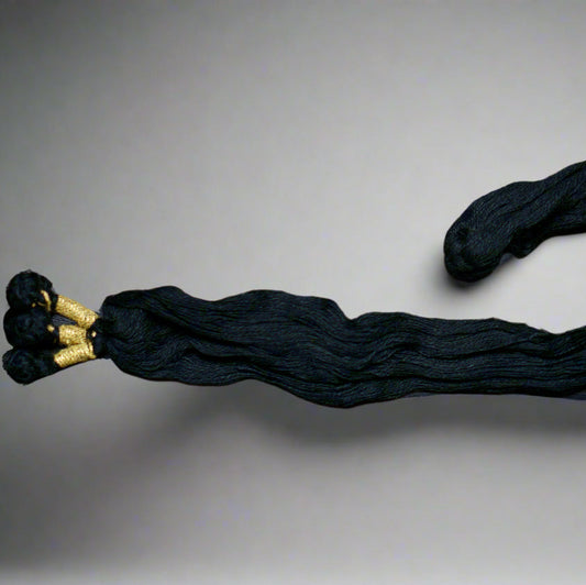 Black hair extensions with gold ends on a gray background